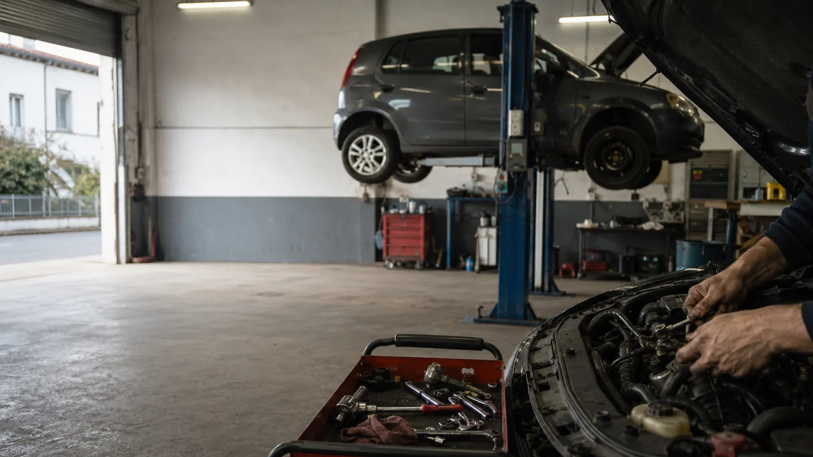 Atelier de mécanique automobile français, véhicule sur pont élévateur et servante à outils